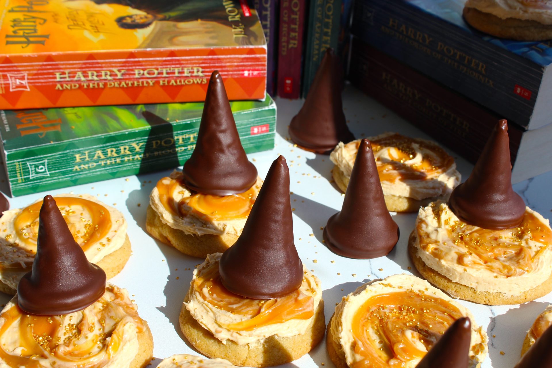 Butterscotch Cookies decorated to look like wizard hats using cone-shaped chocolates on top of swirled peanut butter on round crackers, next to a stack of harry potter books.