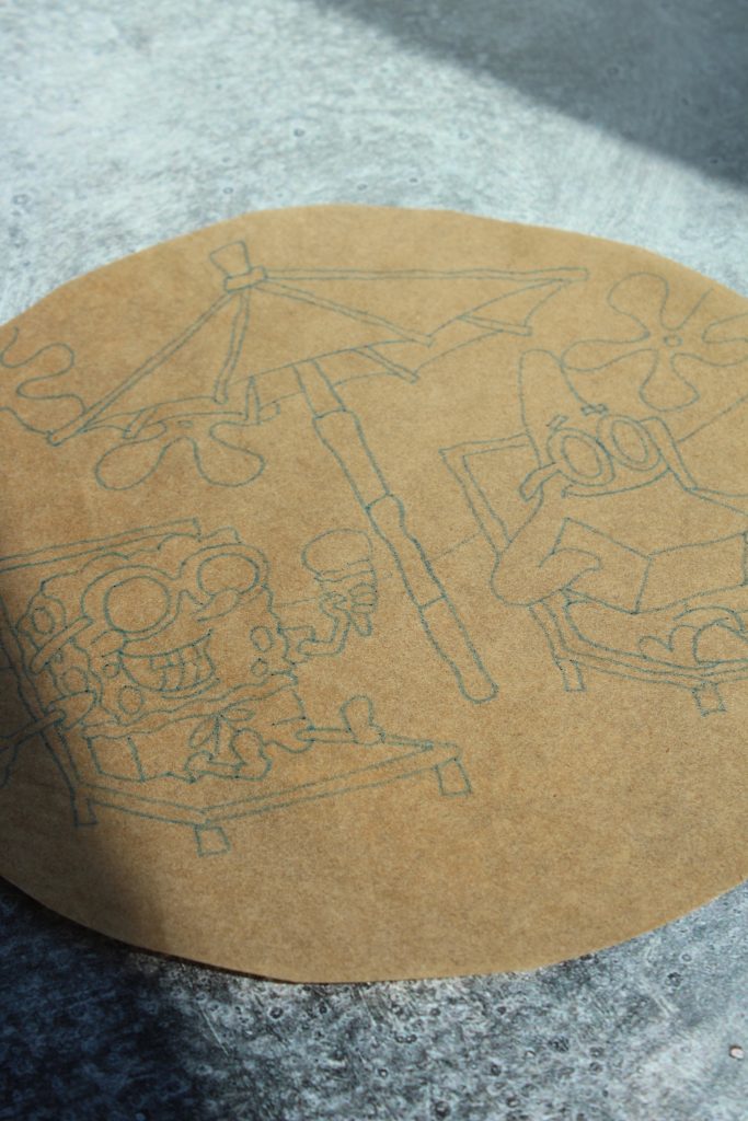 A circular piece of parchment paper with an outline drawing of two animated characters, one holding an ice cream and the other under an umbrella. Both are sitting on lounge chairs, with a sunny, beach-like background suggested.